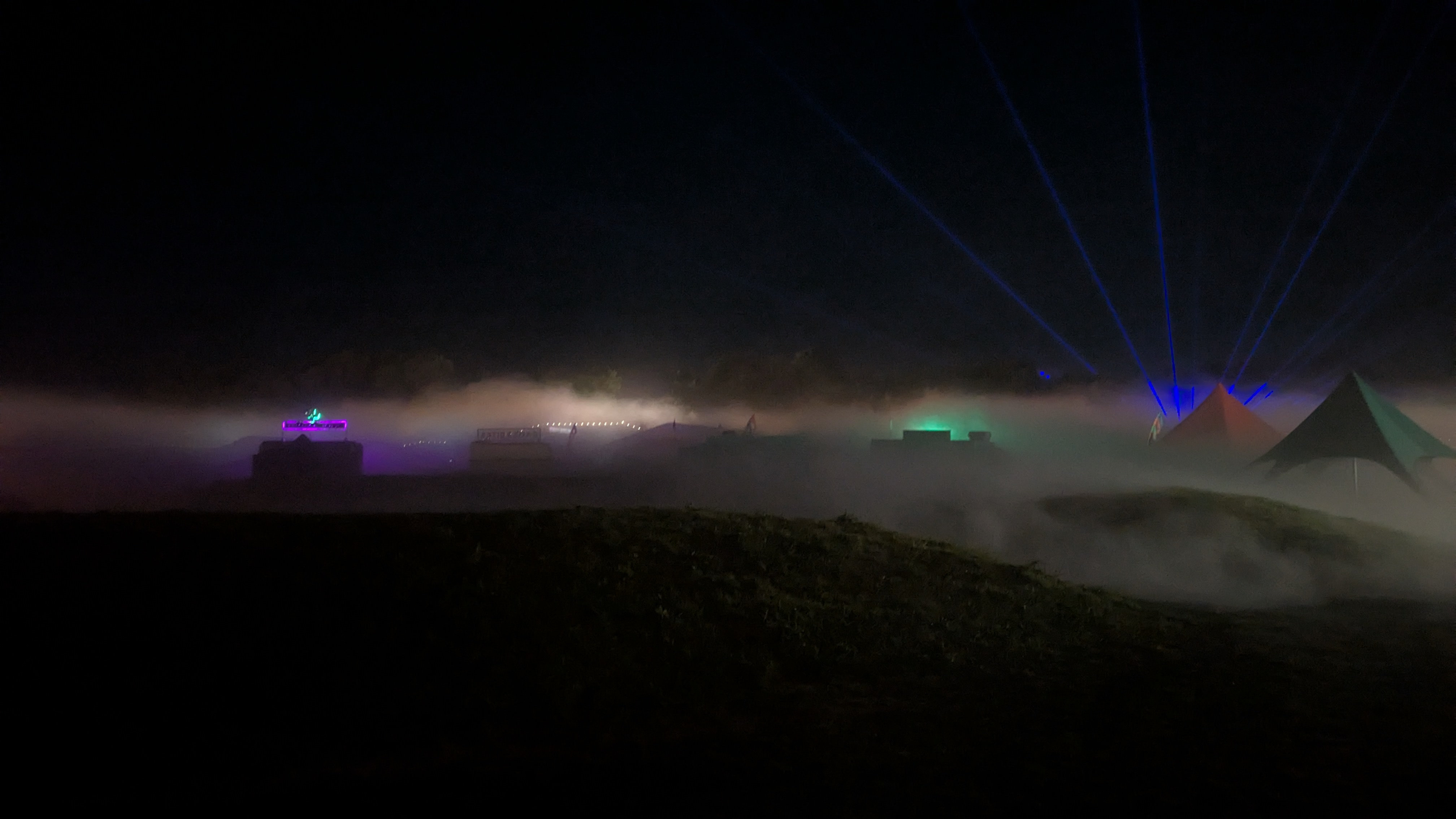 Fog on the hills with lights peeking through it, but no fog in the foreground